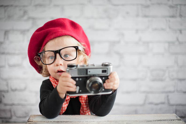 Porträt eines Kleinkinds mit Mütze und Kamera
