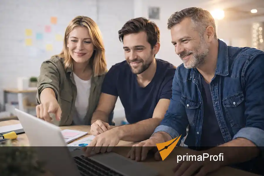 Drei junge Personen arbeiten gemeinsam an einem Laptop in moderner Büro-Umgebung