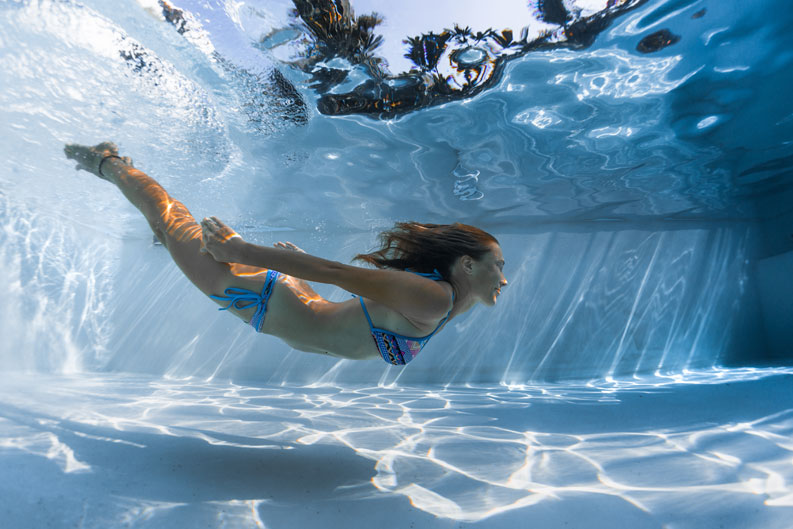 Junge Frau schwimmt im eigenen Pool